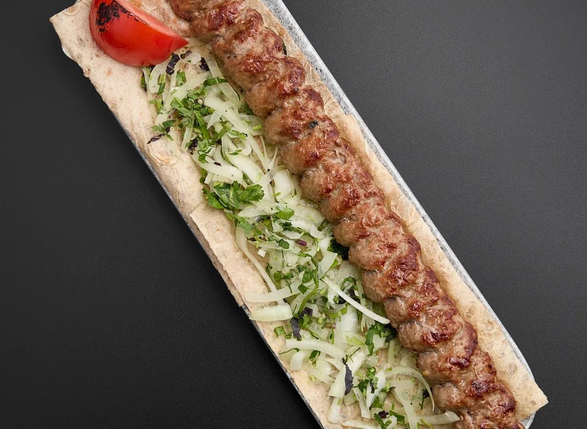 Ktoor kebab on lavash with onion, herbs and a grilled tomato
