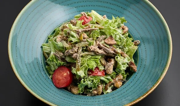 Ktoor salad with meat, greens and tomato in a blue bowl
