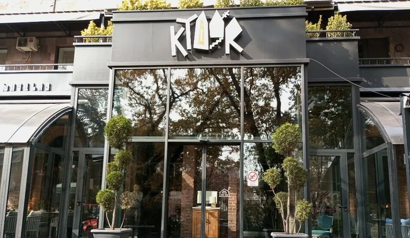 The glass facade on Saryan Street under the Ktoor sign, with potted trees by the door