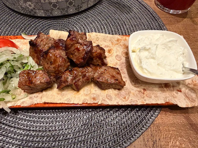 Khorovats pieces on lavash with garlic sauce on the side