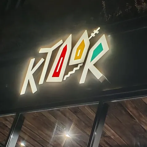 The lit Ktoor sign with its two little houses